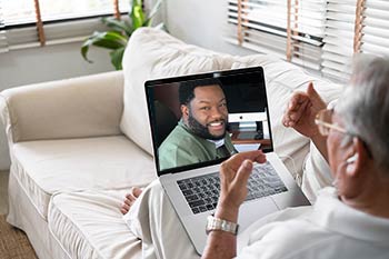 A man teleconferences with Dr. Bannister on a Laptop Computer